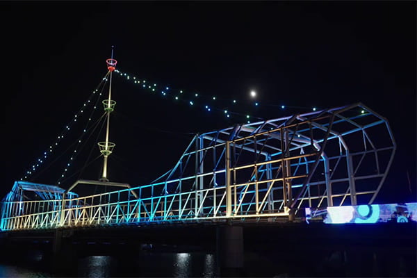 A city skyline at night with a lit bridge as the focal point